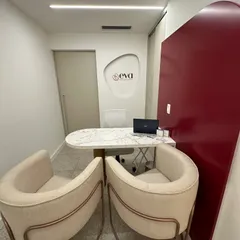 Recepção da clínica Eva com mesa em mármore, cadeiras estofadas e painel acolhedor